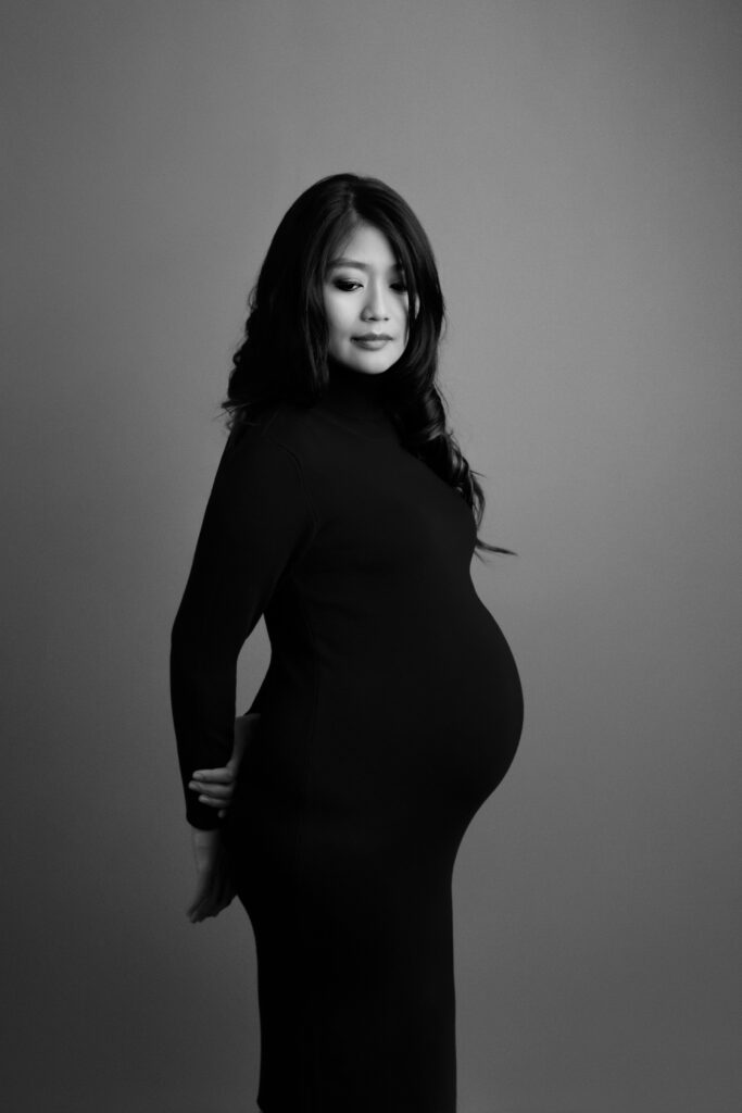 Maternity picture of a woman dressed in a black fitting dress.